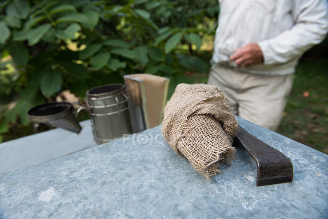 Крупный план курильщика пчел и оборудования в пасечном саду — стоковое фото