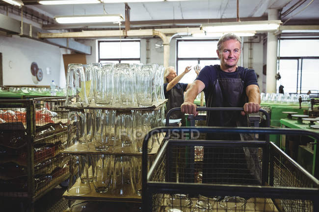 Старший стеклодув толкает тележку на стеклодувном заводе — стоковое фото