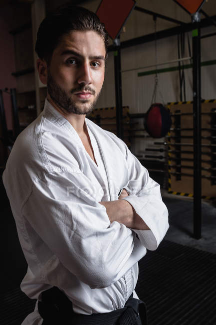 Retrato de homem em karategi de pé com os braços cruzados no estúdio de fitness — Fotografia de Stock