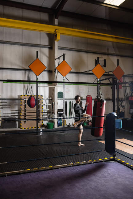 Boxer practicing boxing with punching bag in fitness studio — Stock Photo