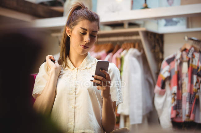 Жінка, що використання мобільного телефону при здійсненні покупок в бутік-магазині — стокове фото
