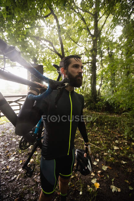 Спортсмен, що перевозить велосипед у лісі — стокове фото