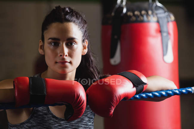Porträt eines attraktiven Boxers in Handschuhen, der sich im Fitnessstudio an das Seil des Boxrings lehnt — Stockfoto