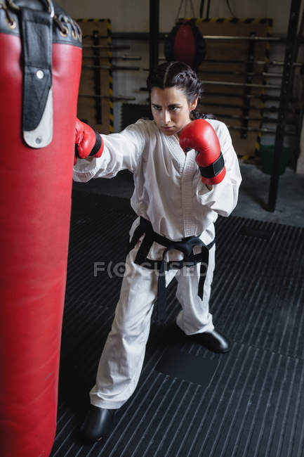 Enfoque selectivo de la mujer practicando karate con saco de boxeo en el gimnasio - foto de stock