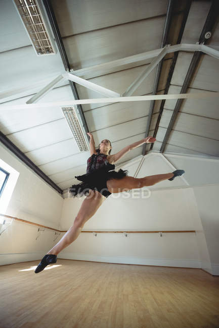 Vista a basso angolo della Ballerina che pratica danza classica e salta in studio — Foto stock