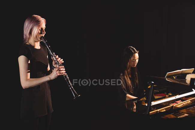 Студенты, играющие на кларнете и пианино в музыкальной школе — стоковое фото