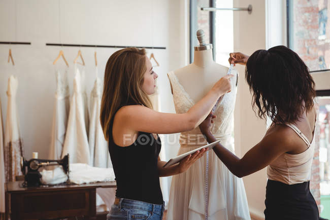 Female fashion designers working on digital tablet in the studio — Stock Photo