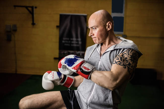 Handsome tattooed Thai boxer practicing boxing in gym — Stock Photo