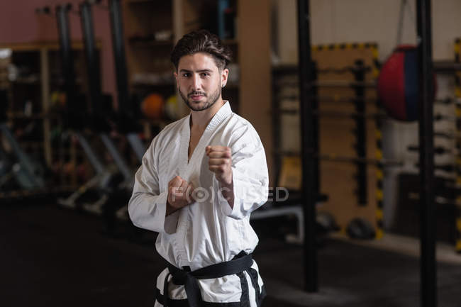 Portrait of man practicing karate in fitness studio and looking at camera — Stock Photo