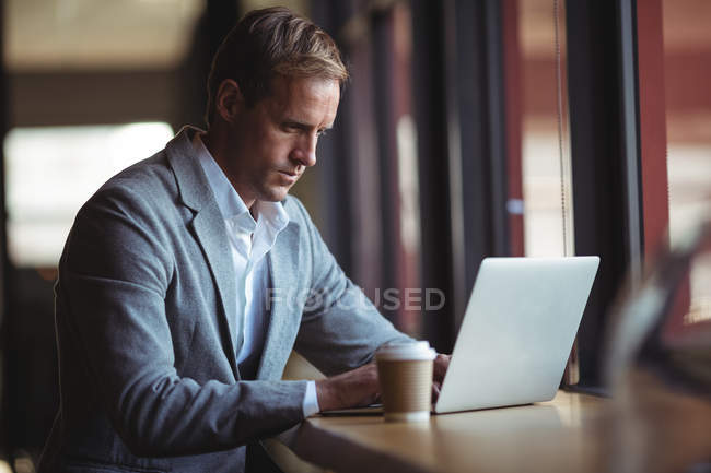 Впевнений бізнесмен працює на ноутбуці з кавою на столі — стокове фото