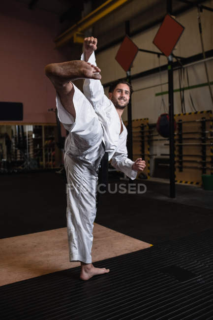 Улыбающийся мужчина практикует карате в фитнес-студии — стоковое фото