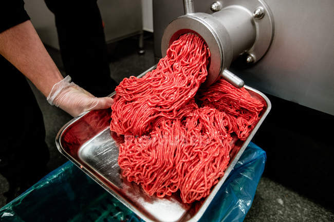 Minced meat coming out from grinder at butchers shop — Stock Photo