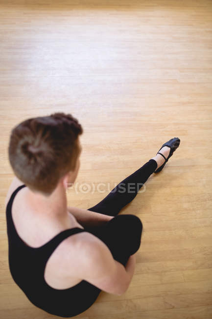 Vue grand angle de Ballerino s'étirant sur le sol en bois dans le studio de ballet — Photo de stock