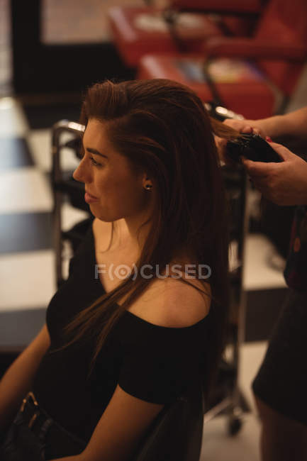 Mujer consiguiendo pelo alisado en peluquería - foto de stock