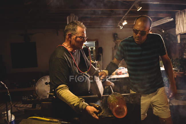 Team of glassblowers shaping molten glass at glassblowing factory — Stock Photo