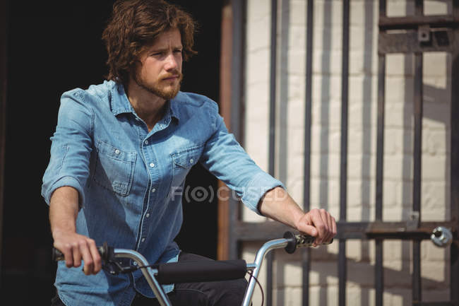 Hombre guapo montando bicicleta en un día soleado - foto de stock