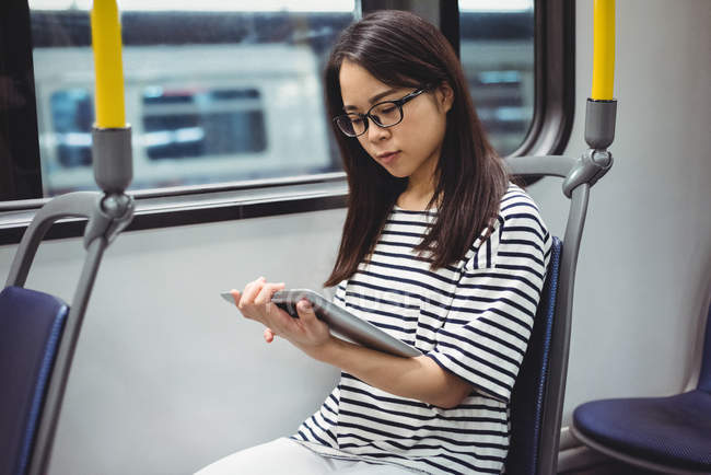 Jovem mulher usando tablet digital no trem — Fotografia de Stock