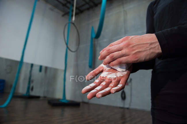 Ginnasta sfregamento polvere di gesso sulle mani in palestra — Foto stock