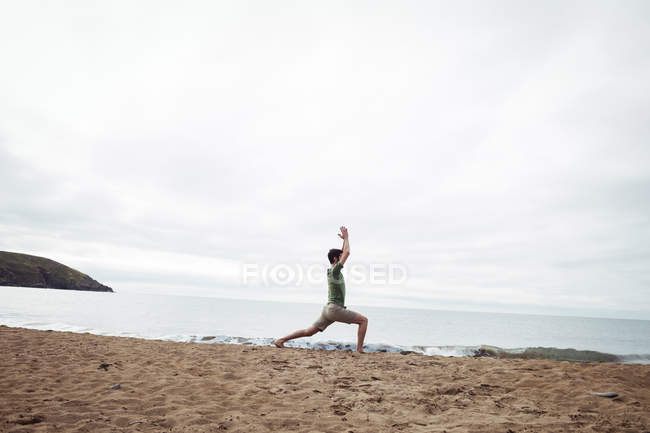 Man performing stretching exercise on beach — Stock Photo