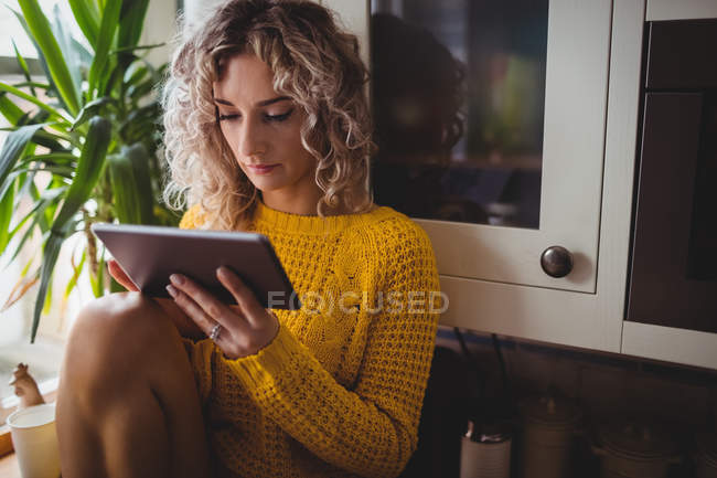 Hermosa mujer usando tableta digital en la cocina en casa - foto de stock