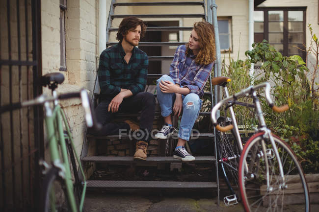 Casal sentado nas escadas e interagindo fora da casa — Fotografia de Stock