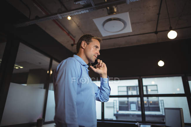 Hombre de negocios hablando en el teléfono móvil en la oficina - foto de stock