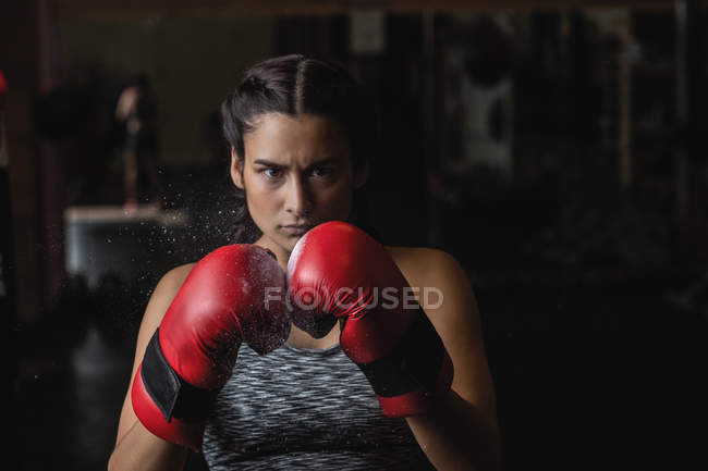 Retrato de mulher em luvas de boxe olhando para a câmera no estúdio de fitness — Fotografia de Stock