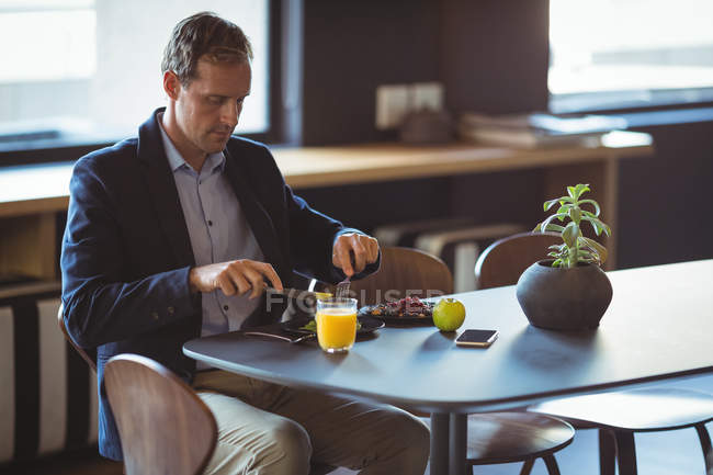 Smart businessman having breakfast in restaurant — Stock Photo