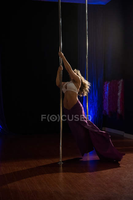 Desportivo Pole dançarina praticando pole dance em estúdio — Fotografia de Stock