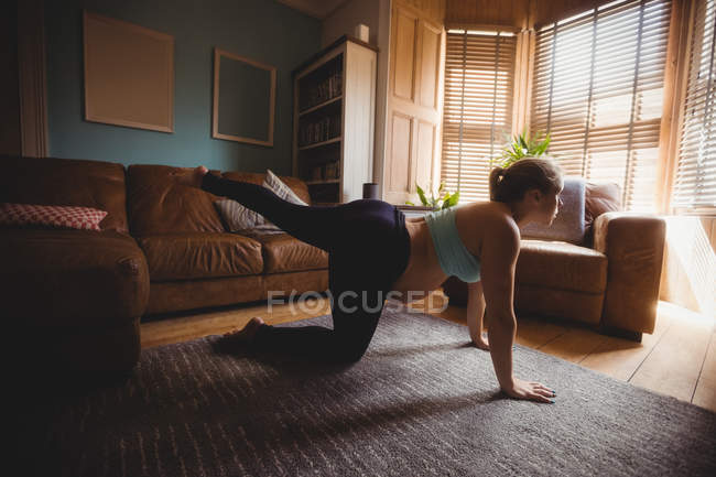 Mulher grávida realizando exercício de alongamento na sala de estar em casa — Fotografia de Stock