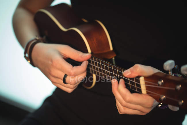 Sección media de la mujer tocando una guitarra en la escuela de música - foto de stock
