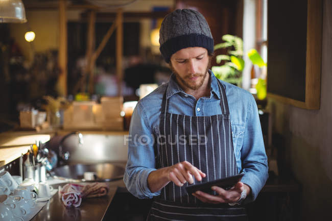 Handsome waiter using digital tablet at counter in workshop — Stock Photo