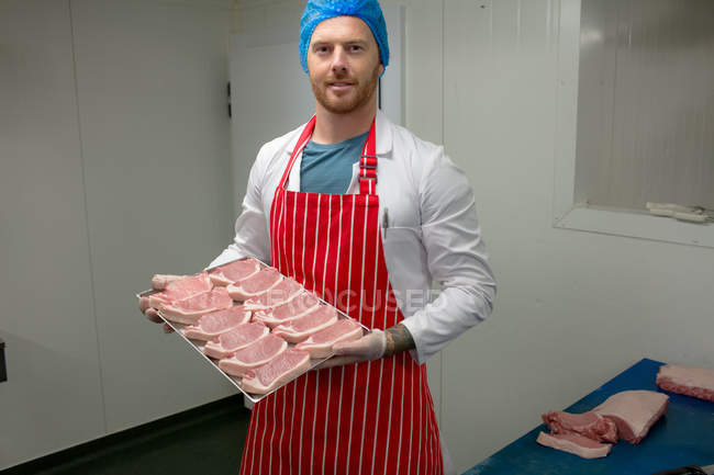 Male butcher holding a tray of steaks at butchers shop — Stock Photo