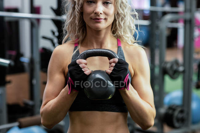 Beautiful woman lifting kettlebell at gym — Stock Photo