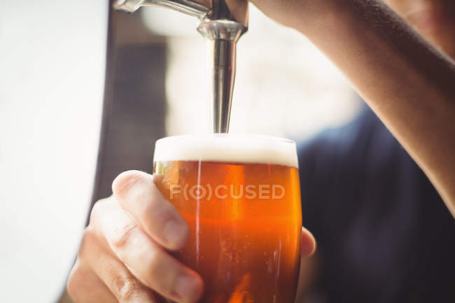 Nahaufnahme des Bartenders, der Bier von der Zapfsäule an der Theke füllt — Stockfoto