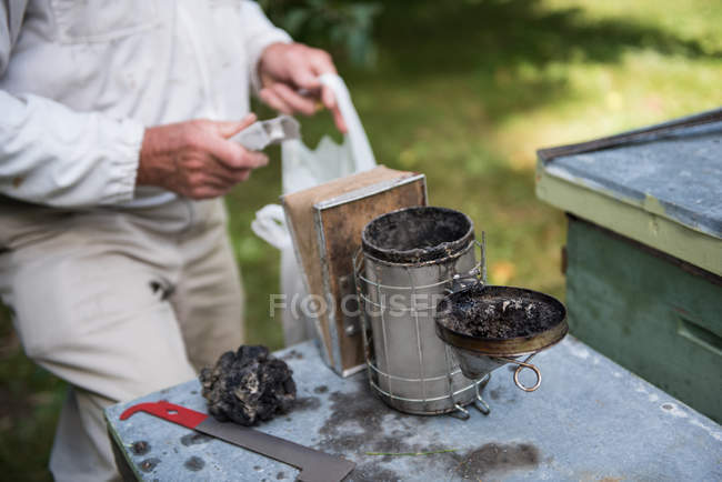 Крупный план курильщика пчел и оборудования в пасечном саду — стоковое фото