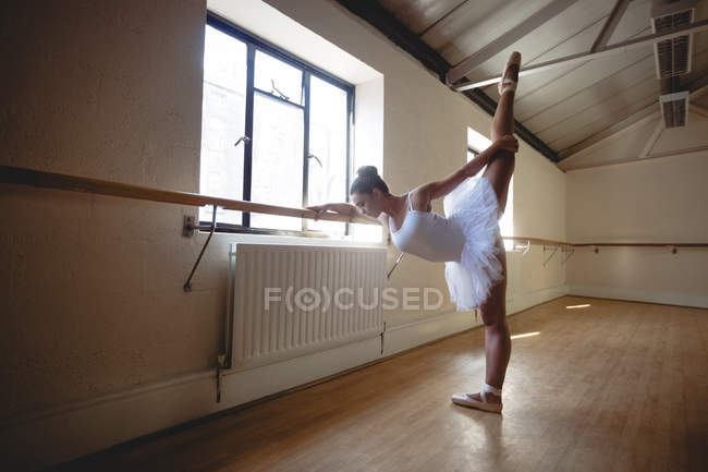 Jeune ballerine pratiquant la danse de ballet à la barre en studio — Photo de stock