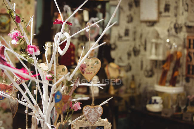 Verschiedene herzförmige Dekorationen hängen an einem gefälschten Zweig in einem Antiquariat — Stockfoto