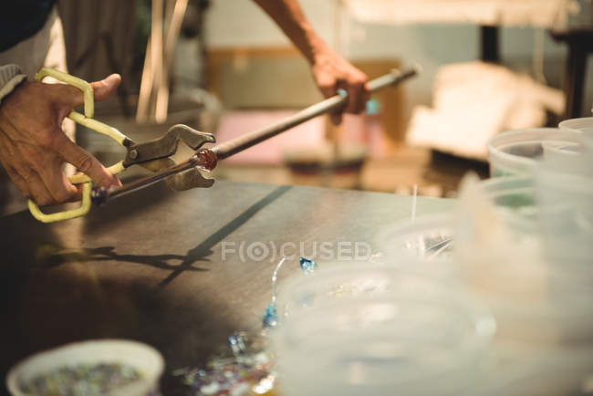 Glassblower holding blowpipe with diamond shears at glassblowing factory — Stock Photo