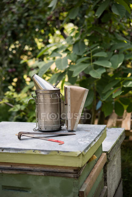 Primer plano de fumador de abejas y equipo en un jardín de colmenas - foto de stock