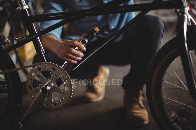 Mécanicien examinant le vélo en atelier — Photo de stock