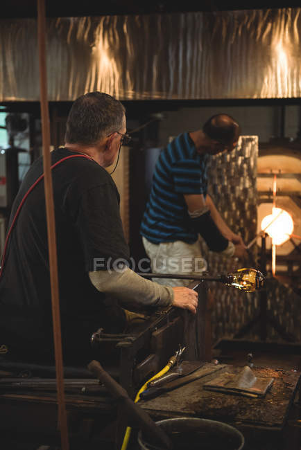 Equipo de sopladores de vidrio que calientan el vidrio en el horno en la fábrica de soplado de vidrio - foto de stock