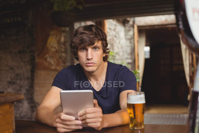Ritratto di uomo con tavoletta digitale con bicchiere da birra sul tavolo al bar — Foto stock