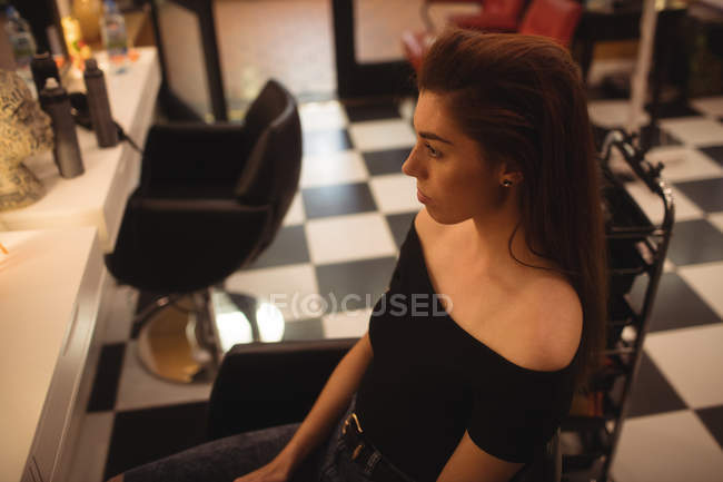 Femme réfléchie assise au salon de coiffure — Photo de stock