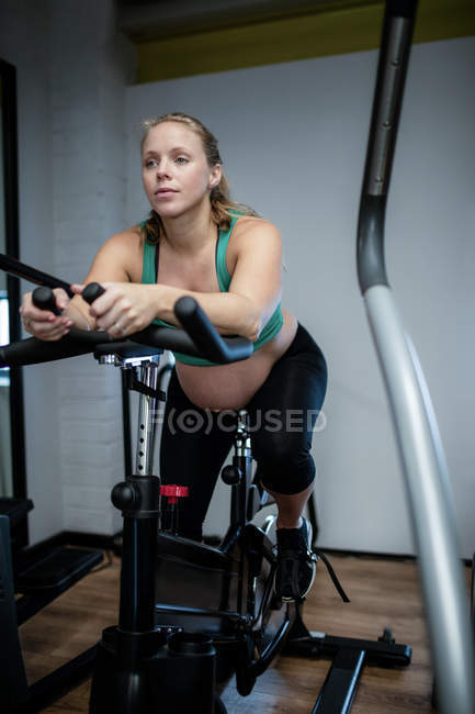 Pregnant woman working out on exercise bike at gym — Stock Photo