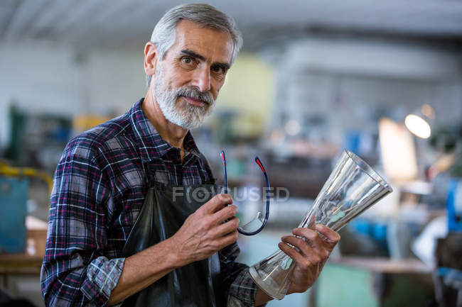 Портрет стеклодува, держащего стеклянную вазу на стекольном заводе — стоковое фото