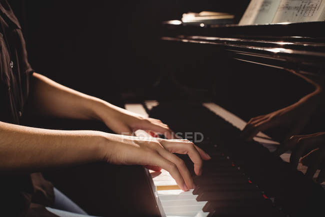 Средняя часть студентки, играющей на фортепиано в студии — стоковое фото