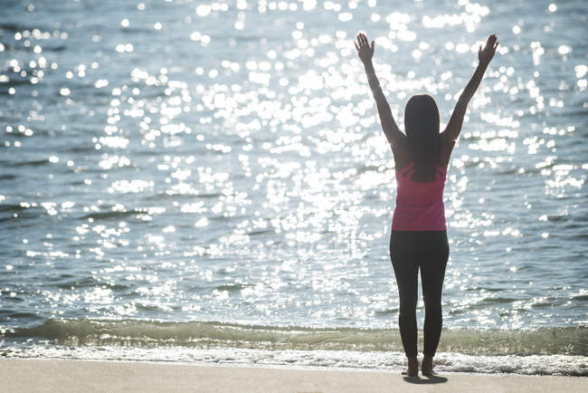 Vue arrière de la femme pratiquant le yoga sur la plage le jour ensoleillé — Photo de stock