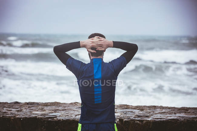 Vista trasera del atleta mirando al mar - foto de stock