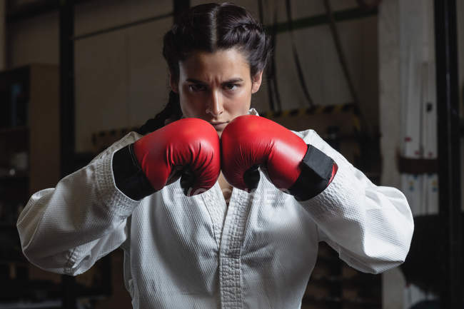 Retrato de boxeador feminino confiante em luvas de boxe vermelhas no estúdio de fitness — Fotografia de Stock